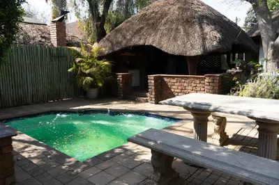 a small swimming pool with a bench and a thatch roof at Manor House at Harties Lodge - Meerhof in Hartbeespoort