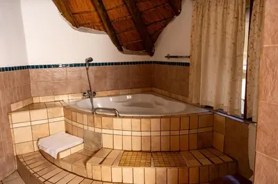 a bath tub in a tiled bathroom with a shower at Manor House at Harties Lodge - Meerhof in Hartbeespoort