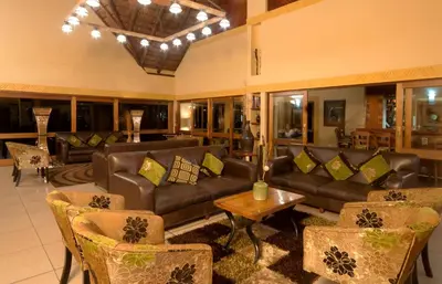 a living room with couches and a table and chairs at Hannah Game Lodge in Ohrigstad