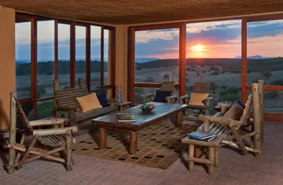 a screened in porch with a table and chairs and a sunset at Hannah Game Lodge in Ohrigstad