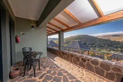 a balcony with a table and chairs and a large window at Hannah Game Lodge in Ohrigstad