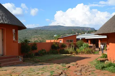 a group of buildings with a mountain in the background at Bama Lodge in Ohrigstad