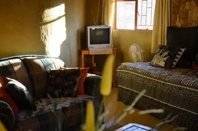a living room with a couch and a tv at Bama Lodge in Ohrigstad