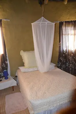 a bedroom with a bed with a mosquito net at Bama Lodge in Ohrigstad