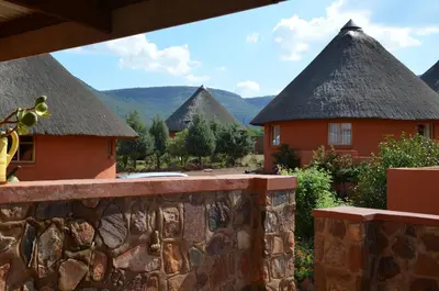 a resort with thatched roofs and a stone wall at Bama Lodge in Ohrigstad