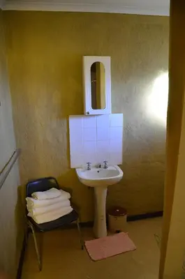 a bathroom with a sink and a mirror and a chair at Bama Lodge in Ohrigstad