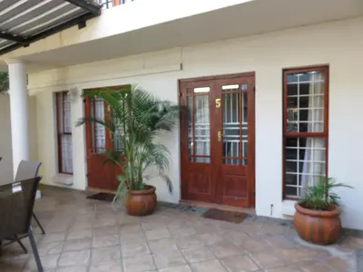 a house with wooden doors and potted plants on a patio at Harties Lodge - Bay View 4 in Hartbeespoort
