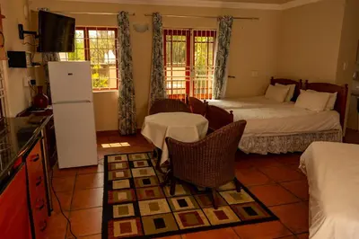 a room with two beds and a kitchen with a refrigerator at Harties Lodge - Meerhof Bay View 6 in Hartbeespoort