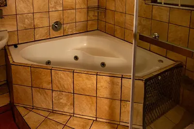 a bath tub in a bathroom with a tiled wall at Harties Lodge - Meerhof Bay View 6 in Hartbeespoort