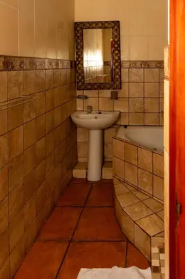 a bathroom with a sink and a tub and a mirror at Harties Lodge - Meerhof Bay View 6 in Hartbeespoort
