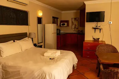 a bedroom with a bed and a table and a refrigerator at Harties Lodge - Meerhof Bay View 7 Family Room in Hartbeespoort