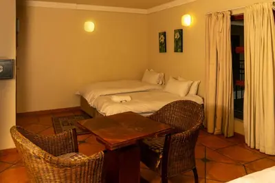 a room with a bed and a table and chairs at Harties Lodge - Meerhof Bay View 7 Family Room in Hartbeespoort