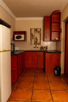 a kitchen with red cabinets and a white refrigerator at Harties Lodge - Meerhof Bay View 7 Family Room in Hartbeespoort