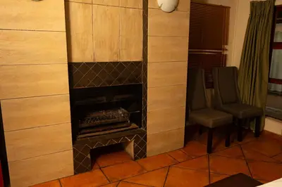 a living room with a fireplace and two chairs at Bay View 9 at Harties Lodge - Meerhof in Hartbeespoort