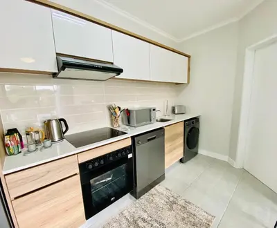 a kitchen with white cabinets and a black dishwasher at 1 Bed in Waterfall - Book 4 & Get 5th Night FREE in Midrand