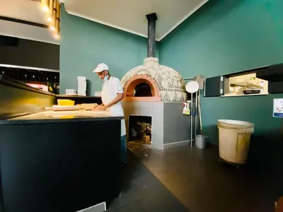 a man standing in a kitchen with a pizza oven at 1 Bed in Waterfall - Book 4 & Get 5th Night FREE in Midrand