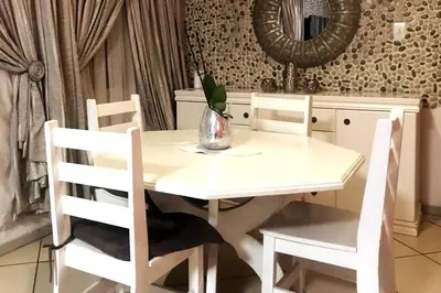 a white dining room table with chairs and a mirror at Modern style Apartment in Pretoria-Central in Pretoria