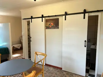 a sliding barn door in a room with a table and chairs at Green Cottage in Haenertsburg