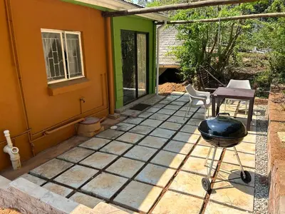 a patio with a grill and a house at Green Cottage in Haenertsburg