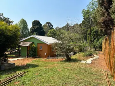 a small green and orange house in a yard at Green Cottage in Haenertsburg