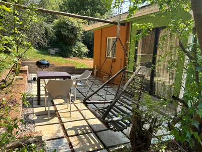 a patio with a table and chairs in front of a house at Green Cottage in Haenertsburg