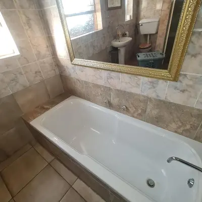 a white bath tub in a bathroom with a mirror at Capital Hill Stay at Spa in Pretoria