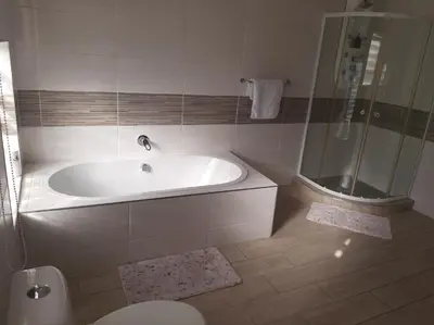 a white bathroom with a tub and a shower at Bonfai Residence in Ermelo