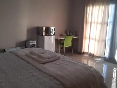 a bedroom with a bed and a refrigerator and a table at Bonfai Residence in Ermelo