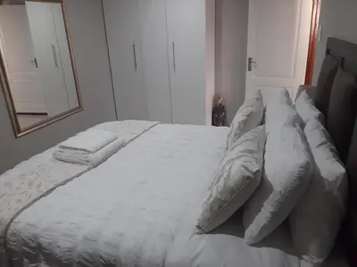 a large white bed with pillows and a mirror at Bonfai Residence in Ermelo