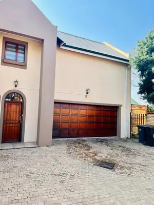 a house with two garage doors and a driveway at Petalsoft in Pretoria