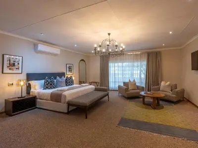 a large bedroom with a bed and a chandelier at The Stella Guest House & Spa in Ermelo