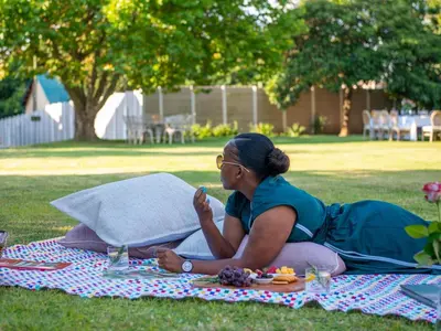 a woman sitting on a picnic blanket on the grass at The Stella Guest House & Spa in Ermelo