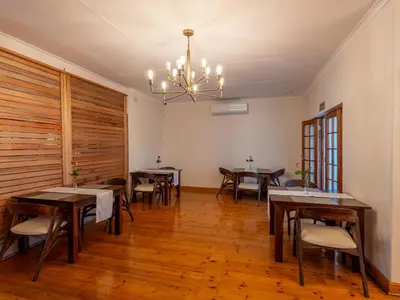 a dining room with tables and chairs and a chandelier at The Stella Guest House & Spa in Ermelo