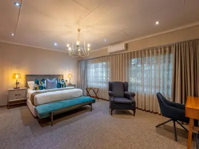a bedroom with a bed and a desk and a chair at The Stella Guest House & Spa in Ermelo