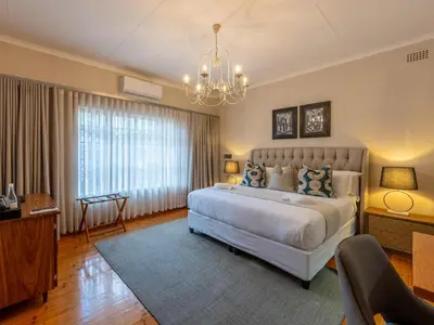 a bedroom with a large white bed and a chandelier at The Stella Guest House & Spa in Ermelo