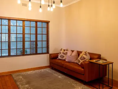 a living room with a brown couch and a window at The Stella Guest House & Spa in Ermelo