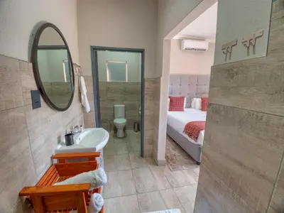 a bathroom with a sink and a mirror and a bed at Tembo Guest Lodge in Hazyview