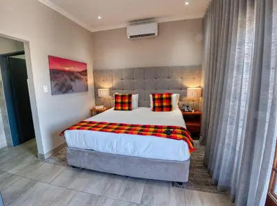 a bedroom with a large bed with plaid pillows at Tembo Guest Lodge in Hazyview