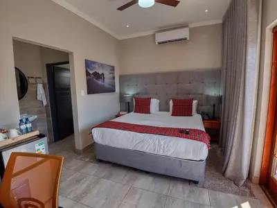 a bedroom with a large bed with red pillows at Tembo Guest Lodge in Hazyview