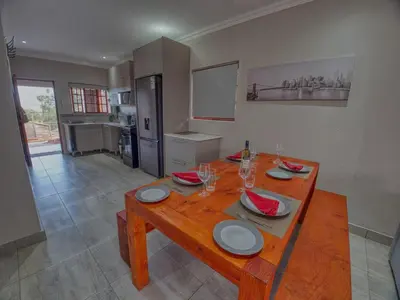 a wooden table with plates and glasses on it in a kitchen at Tembo Guest Lodge in Hazyview