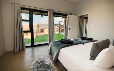 a bedroom with two beds and a large window at Highland Gate Golf and Trout Estate 857 in Dullstroom