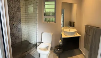 a bathroom with a toilet and a sink and a shower at Whitehouse cottage in White River