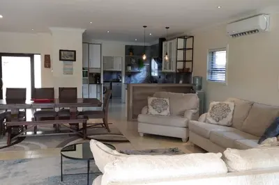 a living room with couches and a dining room at Pecanwood Treasure Hartbeespoort Dam in Hartbeespoort