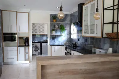 a large kitchen with white cabinets and appliances at Pecanwood Treasure Hartbeespoort Dam in Hartbeespoort