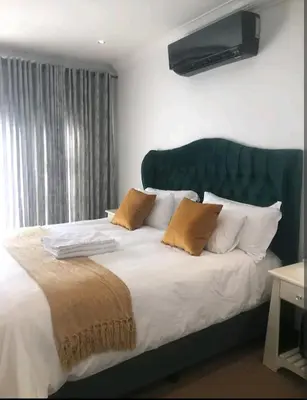 a bedroom with a large bed with a green headboard at Pecanwood Treasure Hartbeespoort Dam in Hartbeespoort