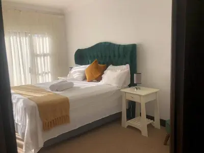 a bed with a green headboard next to a table at Pecanwood Treasure Hartbeespoort Dam in Hartbeespoort
