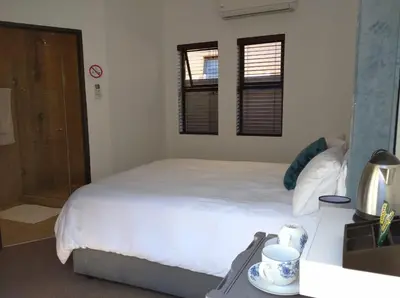 a bedroom with a large white bed and two windows at Pecanwood Treasure Hartbeespoort Dam in Hartbeespoort