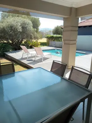 a table with chairs and a swimming pool at Pecanwood Treasure Hartbeespoort Dam in Hartbeespoort