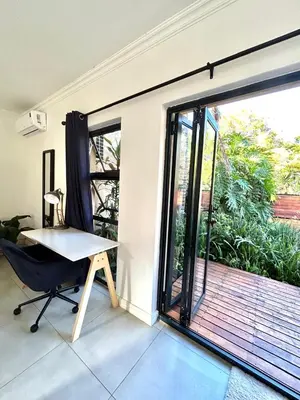 an office with a desk and a large sliding glass door at Apartment close to Menlyn Maine in Pretoria