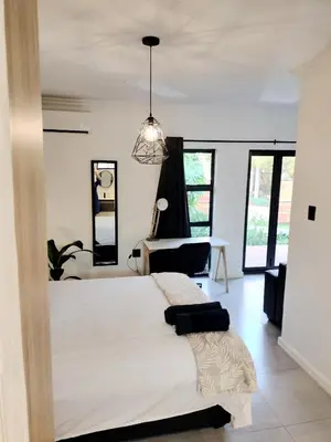 a bedroom with a large bed in a room with windows at Apartment close to Menlyn Maine in Pretoria